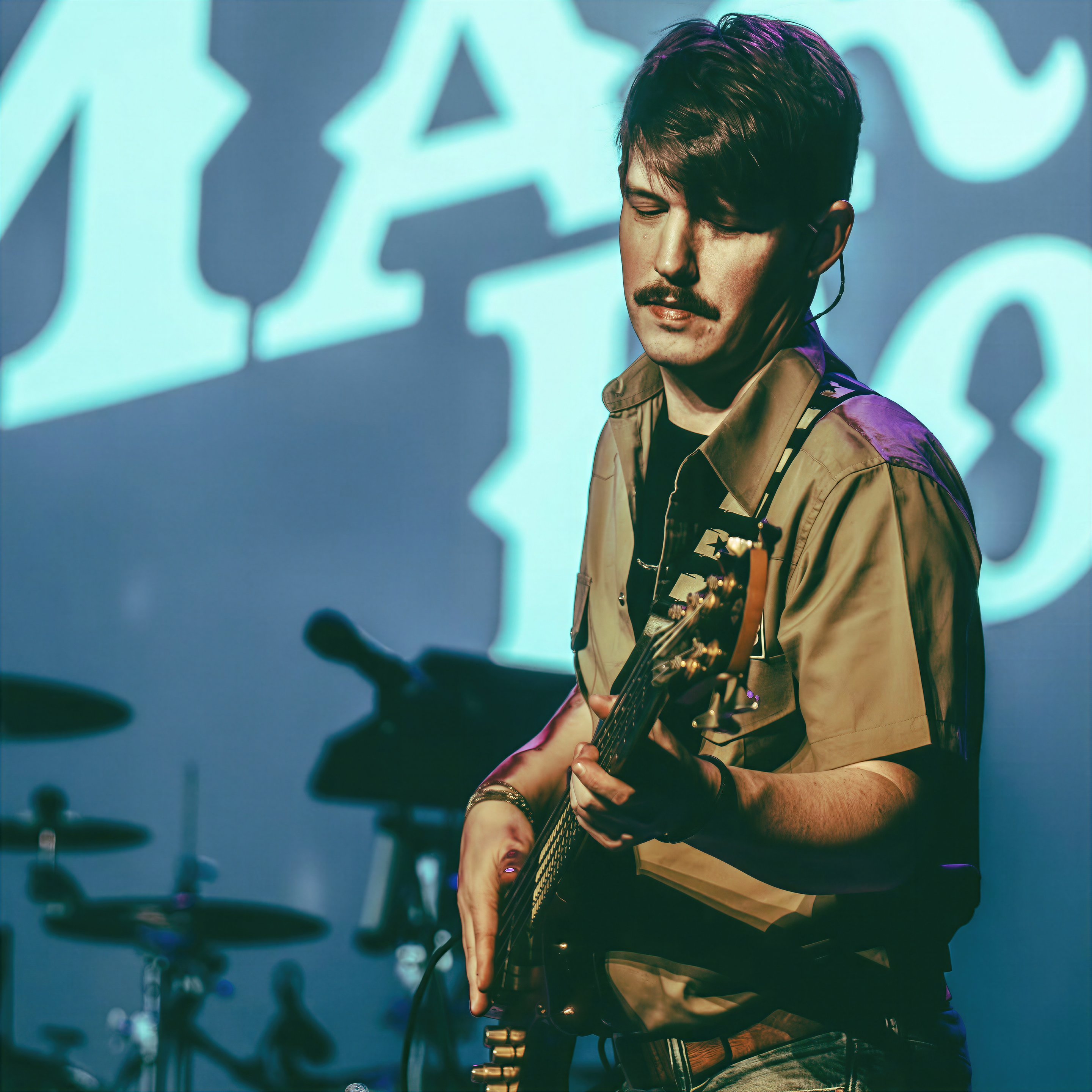 Dan Beattie playing bass live on stage in front of The Martin Boys logo